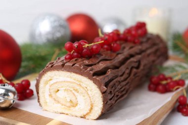 Lezzetli Noel kütüğü (geleneksel Noel pastası) kırmızı üzümlü ve dekorlu, yakın plan.