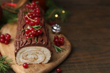 Lezzetli Noel kütüğü (geleneksel Noel pastası) ahşap masa üzerinde kırmızı frenk üzümü, yakın plan. Metin için boşluk