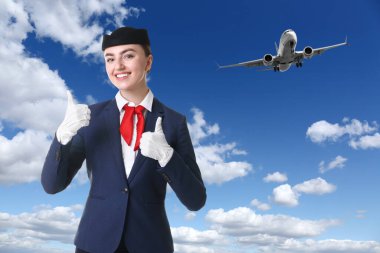 Mavi gökyüzüne karşı üniformalı mutlu hostes.