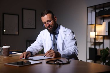 Doktor, gece vardiyası sırasında klinikteki masada notlar yazıyor.