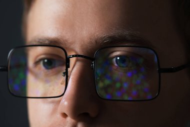 Karanlık arka planda yansıması olan gözlüklü bir adam, yakın plan.