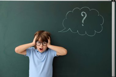 Okula dönelim. Düşünce baloncuğu ve soru işareti çizilmiş karatahtanın yanındaki duygusal çocuk