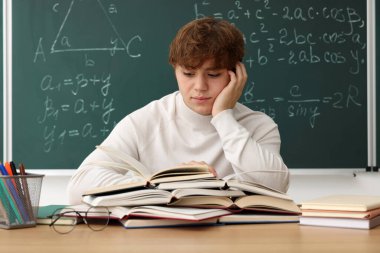 Okula dönelim. Tahta masada matematik ödevi ile çalışan öğrenci.