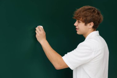 Okula dönelim. Yeşil karatahtaya tebeşirle yazı yazan öğrenci, metin için boşluk