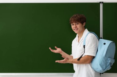 Okula dönelim. Sırt çantalı öğrenci yazı tahtasının yanında, metin için boşluk