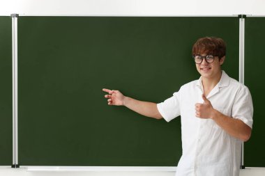 Okula dönelim. Mutlu çocuk yazı tahtasının yanında başparmak gösteriyor, metin için boşluk var.