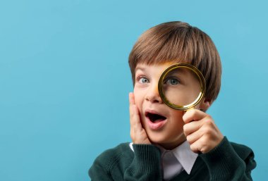 Açık mavi arka planda büyüteç olan küçük bir çocuk. Metin için boşluk
