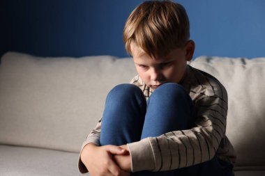 Üzgün küçük çocuk kanepenin içinde oturuyor, mesaj için yer var.