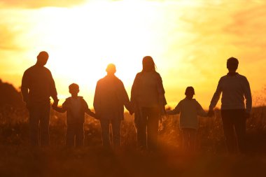 Aile gün batımında el ele tutuşuyor.