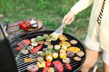 Vejetaryen barbeküsü. Dışarıdaki ızgarada sebze pişiren kadın, yakın plan.