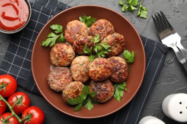 Koyu dokulu masada servis edilen maydanozlu, domatesli ve ketçaplı leziz köfteler.