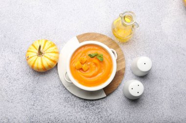 Gri masada servis edilen fesleğenli lezzetli balkabağı kremalı çorba.