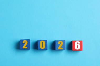 Yeni yıl 2026. Açık mavi arkaplanda rakamları olan tahta küpler, üst görünüm