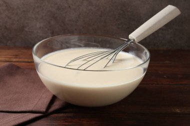 Sıvı hamur kasede ve çırpı ahşap masada, yakın plan.