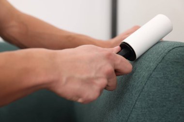 Evdeki pamuklu bezle kanepeyi temizleyen adam, yakın çekim.