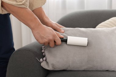 Evdeki kanepede pamuklu bezle yastığı temizleyen adam, yakın plan.