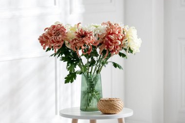 İçerideki kahve masasında vazoda güzel kasımpatı çiçekleri var.