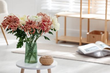 İçerideki sehpada vazoda güzel kasımpatı çiçekleri, metin için yer.