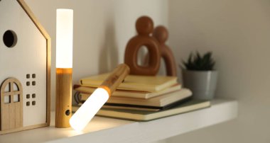 Portatif LED lambalar, kitaplar ve dekorlar beyaz rafta, yakın plan