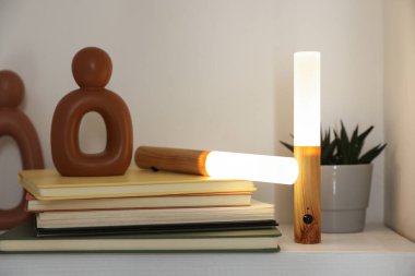 Portatif LED lambalar, kitaplar ve dekorlar beyaz rafta, yakın plan