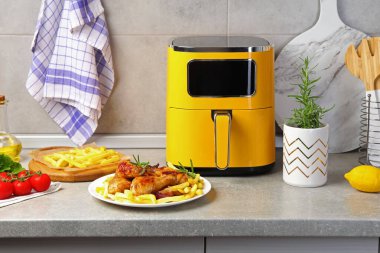 Kızarmış tavuk budu, patates kızartması, malzemeler ve gri tezgahta hava kızartması.