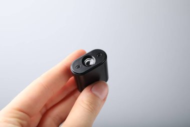 Açık gri arka planda modern casus kamerası tutan kadın, yakın plan.