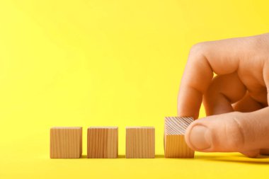 Sarı arka planda tahta küpleri olan adam, yakın plan. Metin için boşluk