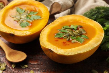 Çekirdekli balkabağı kremalı çorba ve ahşap masada maydanoz, yakın plan.