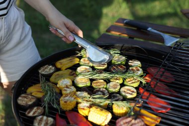 Vejetaryen barbeküsü. Dışarıdaki ızgarada sebze pişiren kadın, yakın plan.