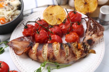 Lezzetli kalamar, mikroyeşiller, limon ve domatesler beyaz masada, yakın plan.