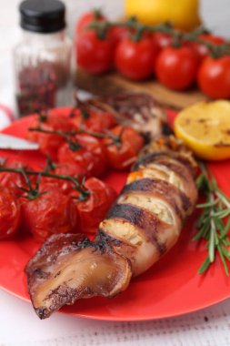 Lezzetli kalamar, biberiye ve domatesler açık ahşap masada, yakın plan.