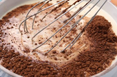 Kakao tozunu hamurla birlikte kaseye ekliyorum, yakın plan.