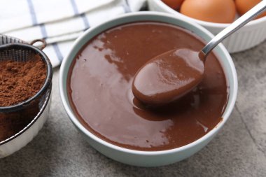 Tabakta sıvı çikolata hamuru ve gri masada malzemeler, yakın plan.