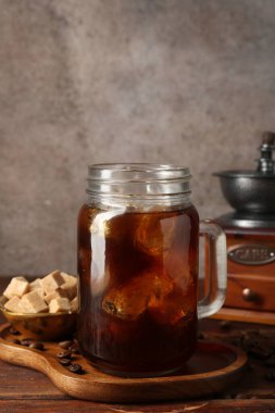 Lezzetli kahve, şeker, öğütücü ve fasulye ahşap masada.