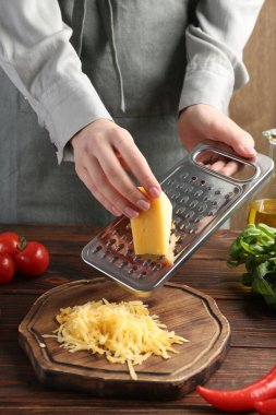 Ahşap masada peynir rendeleyen kadın, yakın plan.