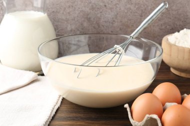 Tabakta sıvı hamur, çırpma ve malzemeler ahşap masada, yakın plan.