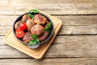 Maydanozlu leziz köfteler ve ahşap masada tavada domatesler. Metin için boşluk