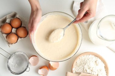 Beyaz masada hamuru yapan kadın (sıvı hamur), üst görünüm