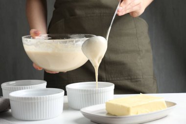 Kadın hamur hamurunu (sıvı hamur) içerideki masada yemek tabaklarına döküyor, yakın plan.