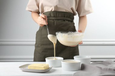 Kadın hamur hamurunu (sıvı hamur) içerideki masada yemek tabaklarına döküyor, yakın plan.