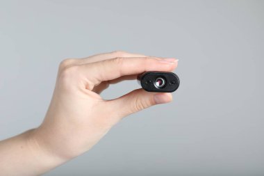 Açık gri arka planda gizli casus kamerası olan kadın, yakın plan.