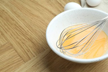 Kavanozda çırpılmış yumurta ve ahşap masada çırpılmış çırpılmış çırpma, yakın plan. Metin için boşluk