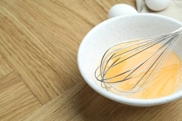 Kavanozda çırpılmış yumurta ve ahşap masada çırpılmış çırpılmış çırpma, yakın plan. Metin için boşluk