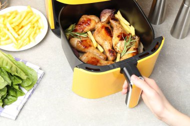 Gri masada tavuklu tavuk budu pişiren bir kadın.