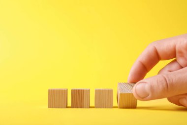 Sarı arka planda tahta küpleri olan adam, yakın plan. Metin için boşluk