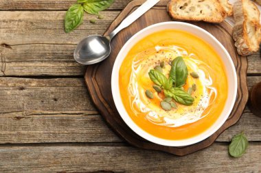 Tahta masada servis edilen fesleğenli ve tohumlu lezzetli balkabağı kremalı çorba.