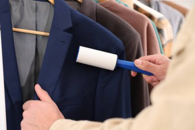 Tiftik silindirli adam ceketini evde temizliyor.