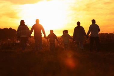 Aile gün batımında, arka planda el ele tutuşuyor.