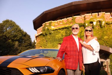 Modern Cabriolet yakınlarında güneş gözlüklü şık bir çift, düşük açılı.