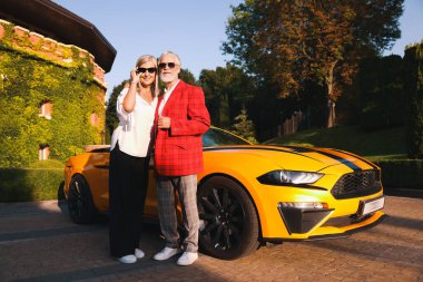 Modern Cabriolet yakınlarında güneş gözlüklü şık bir çift.